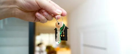 Mão segurando a chave de um imóvel com chaveiro em forma de casa